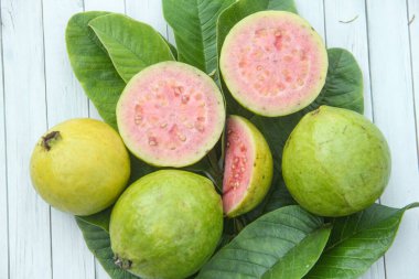 Taze guava ve dilimlenmiş guava yeşil guava yaprakları üzerinde.