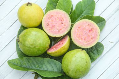 Taze guava ve dilimlenmiş guava yeşil guava yaprakları üzerinde.