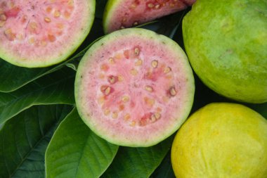Taze guava ve dilimlenmiş guava yeşil guava yaprakları üzerinde.