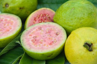 Taze guava ve dilimlenmiş guava yeşil guava yaprakları üzerinde.
