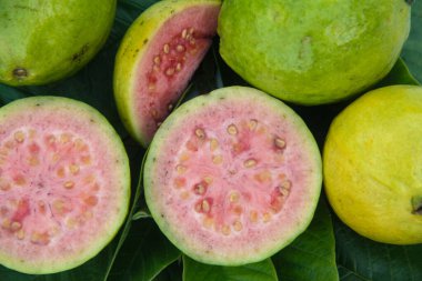 Taze guava ve dilimlenmiş guava yeşil guava yaprakları üzerinde.