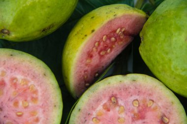 Taze guava ve dilimlenmiş guava yeşil guava yaprakları üzerinde.