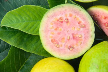 Taze guava ve dilimlenmiş guava yeşil guava yaprakları üzerinde.