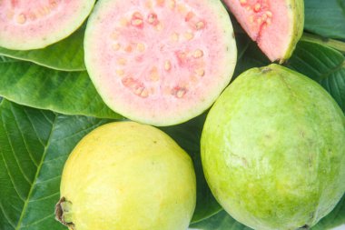 Taze guava ve dilimlenmiş guava yeşil guava yaprakları üzerinde.