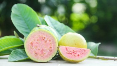 Taze, olgun guava ve dilimlenmiş guava. Tahta masa üzerinde, doğal arka planda.