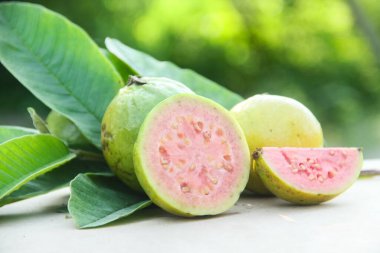 Taze, olgun guava ve dilimlenmiş guava. Tahta masa üzerinde, doğal arka planda.