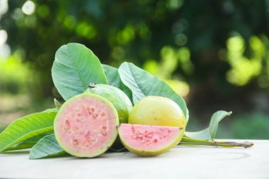 Taze, olgun guava ve dilimlenmiş guava. Tahta masa üzerinde, doğal arka planda.