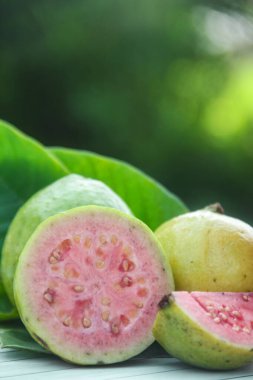 Taze, olgun guava ve dilimlenmiş guava. Tahta masa üzerinde, doğal arka planda.