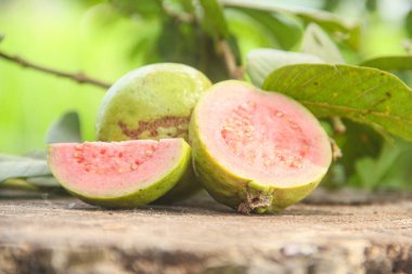 Taze, olgun guava ve dilimlenmiş guava. Tahta masa üzerinde, doğal arka planda.