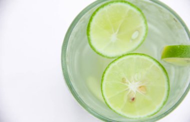 Bir bardak limon dilimli soğuk su, beyaz arka planda izole edilmiş limon dilimli sağlıklı bir içecek.