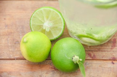 Taze limon dilimli bir bardak soğuk su, ahşap masaya konmuş limon dilimli sağlıklı bir içecek.