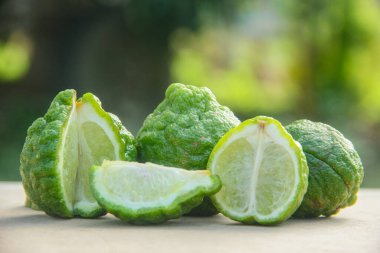 Bergamot meyveleri veya dilimlenmiş kaffir limonu veya ahşap masa ve doğal yeşil arka plan üzerindeki Citrus hystrix.