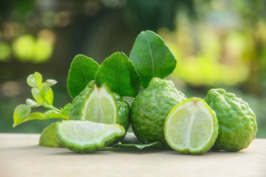 Bergamot meyveleri veya dilimlenmiş kaffir limonu veya ahşap masa ve doğal yeşil arka plan üzerindeki Citrus hystrix.