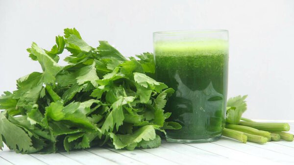 Celery juice, healthy green drink made from celery, green celery smoothie decorated with fresh green celery leaves