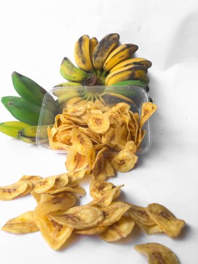 Kepok muz veya musa paradisiaca meyvesi ile süslenmiş ve beyaz bir arkaplanda izole edilmiş muz cipsi serpintisi.