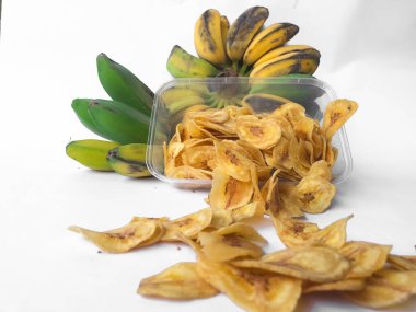 Kepok muz veya musa paradisiaca meyvesi ile süslenmiş ve beyaz bir arkaplanda izole edilmiş muz cipsi serpintisi.