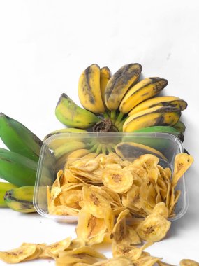 Kepok muz veya musa paradisiaca meyvesi ile süslenmiş ve beyaz bir arkaplanda izole edilmiş muz cipsi serpintisi.