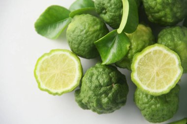 Kaffir limonu ya da bergamot meyvesi, Kaffir limonu ya da narenciye histriks meyvesi dilimlenmiş ve beyaz arka planda yapraklarla süslenmiş.