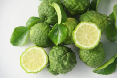 Kaffir limonu ya da bergamot meyvesi, Kaffir limonu ya da narenciye histriks meyvesi dilimlenmiş ve beyaz arka planda yapraklarla süslenmiş.