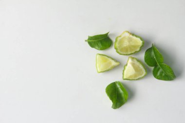 Kaffir limonu ya da bergamot meyvesi, Kaffir limonu ya da narenciye histriks meyvesi dilimlenmiş ve beyaz arka planda yapraklarla süslenmiş.