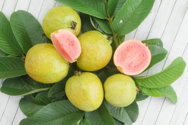 Guava yapraklarıyla süslenmiş kırmızı guava meyveli Psidium Guajava. Olgun ve taze kırmızı guava dilimleri