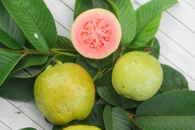 Guava yapraklarıyla süslenmiş kırmızı guava meyveli Psidium Guajava. Olgun ve taze kırmızı guava dilimleri