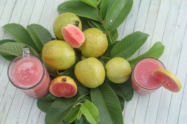 Guava yapraklarıyla süslenmiş kırmızı guava meyveli Psidium Guajava. Olgun ve taze kırmızı guava dilimleri