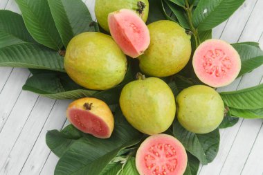Guava yapraklarıyla süslenmiş kırmızı guava meyveli Psidium Guajava. Olgun ve taze kırmızı guava dilimleri