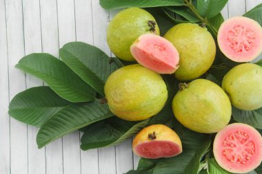 Guava yapraklarıyla süslenmiş kırmızı guava meyveli Psidium Guajava. Olgun ve taze kırmızı guava dilimleri