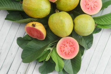 Guava yapraklarıyla süslenmiş kırmızı guava meyveli Psidium Guajava. Olgun ve taze kırmızı guava dilimleri