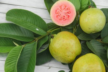 Guava yapraklarıyla süslenmiş kırmızı guava meyveli Psidium Guajava. Olgun ve taze kırmızı guava dilimleri