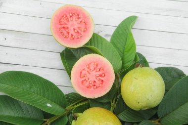 Guava yapraklarıyla süslenmiş kırmızı guava meyveli Psidium Guajava. Olgun ve taze kırmızı guava dilimleri