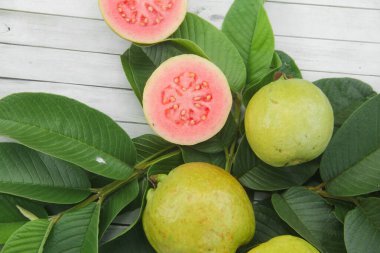Guava yapraklarıyla süslenmiş kırmızı guava meyveli Psidium Guajava. Olgun ve taze kırmızı guava dilimleri
