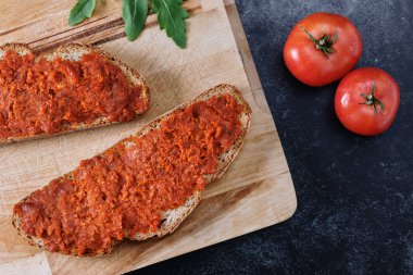 Mayorka 'dan Sobrasada soslu ekmek. Tahta kesme tahtası ve koyu arkaplan üzerindeki üst görünüm