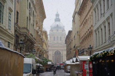 Budapeşte, Macaristan - 30 Kasım 2023: Yılbaşı pazarı ve alışveriş caddesinde karlı bir sabah, şenlik dekorasyonu ve arka planda Aziz Stephen Bazilikası