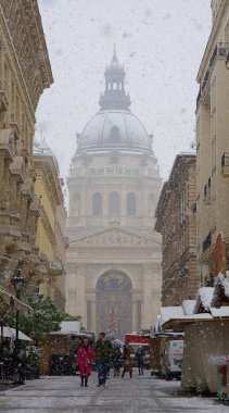 Budapeşte, Macaristan - 30 Kasım 2023: Yılbaşı pazarı ve alışveriş caddesinde karlı bir sabah, şenlik dekorasyonu ve arka planda Aziz Stephen Bazilikası