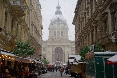 Budapeşte, Macaristan - 30 Kasım 2023: Yılbaşı pazarı ve alışveriş caddesinde karlı bir sabah, şenlik dekorasyonu ve arka planda Aziz Stephen Bazilikası