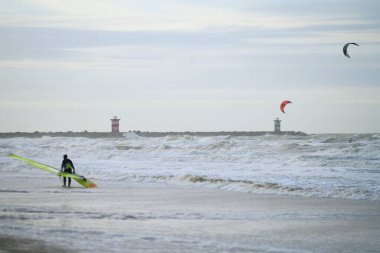 Keizerstraat, 2586 Zen Haag, Hollanda - 23 Aralık 2023: Kışın kuzey denizi. Ön planda sörfçü.
