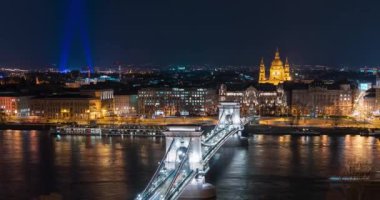 Budapeşte, Macaristan - 13 Mart 2024: Buda tarafından gece zincirli köprü. Işık gösterisi, arka planda Aziz Stephen Bazilikası ve dönme dolap. Zaman aşımı, yakınlaştırma geçişi.