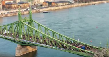 Budapeşte, Macaristan - 15 Mart 2024: Ulusal Gün Kutlaması. Soldaki Özgürlük Köprüsü 'nde siyasi hareketlilik ve sağdaki badem ağacının yanında fotoğraf çeken insanlar. Zaman aşımı, yakınlaştırma.