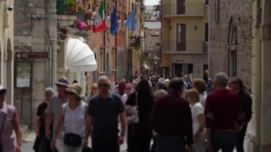 Taormina, İtalya - 19 Mayıs 2024: Ağır çekimde yürüyen insanlar. Corso Umberto Caddesi. Odaklanma arkaplana kaydırıldı.
