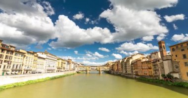 Florence, İtalya - 31 Mayıs 2024: Arno nehri üzerindeki Ponte Vecchio köprüsü. Zaman atlaması. Arka planda dinleme cihazı var. Orta bulutlu gökyüzü.