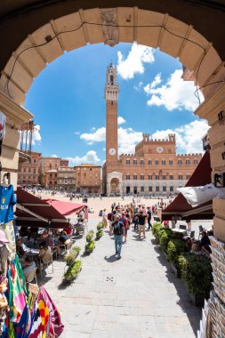 Siena, İtalya - 01 Haziran 2024: Torre del Mangia, Kemer manzaralı. Ön planda turist dükkanı.