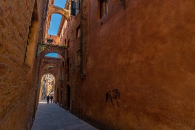 Siena, İtalya - 01 Haziran 2024: Siena 'nın güzel caddesi. Kemerli bina. Aşağıdan yukarıya doğru. At grafitisi..