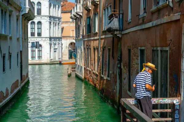 Venedik, İtalya - 4 Haziran 2024 Gandolier kanalın üzerindeki köprüde turistleri bekliyor. Venedik 'te popüler turistik yerler.