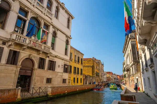 stock image Venice, Italy - June 05, 2024: Venetian Canal with Historic Buildings and Flags.