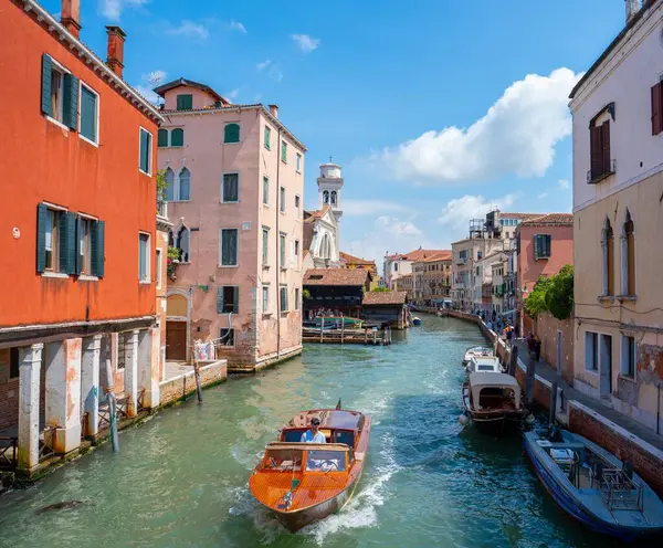 Venedik, İtalya - Haziran 05, 2024: Turuncu botla kanalı geçen adam.