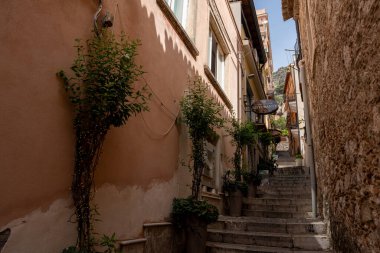 Taormina, İtalya - 19 Haziran 2024: Dar sokaktaki basamaklarda saksı bitkileri.