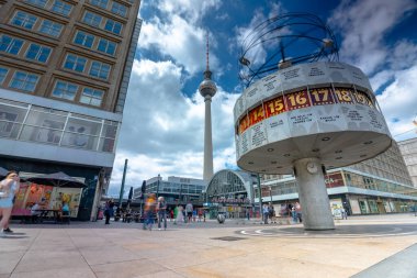 Berlin, Almanya - 23 Haziran 2024: Alexanderplatz Dünya Zaman Saati. Arka planda televizyon kulesi var. Güneşli bir gün, bulutlu bir hava. Uzun pozlu çekim.