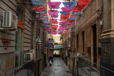 Catania, İtalya - 20 Mayıs 2024: Caddenin üzerindeki sanat: Tepemizde canlı şemsiyelerle süslenmiş bir ara sokak, Catania 'nın yaratıcı ruhunu yakalıyor.